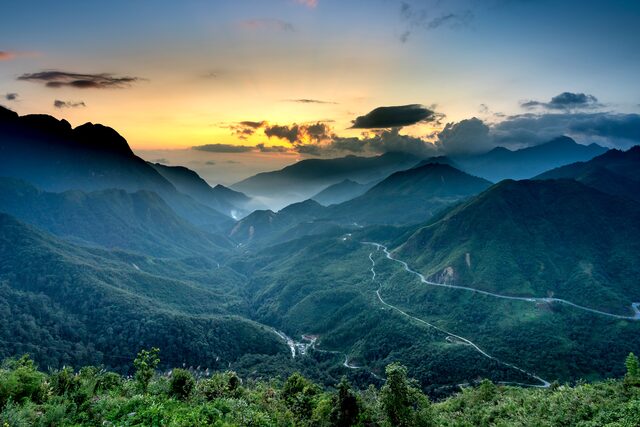 A road winding through a mountain valley at dusk.