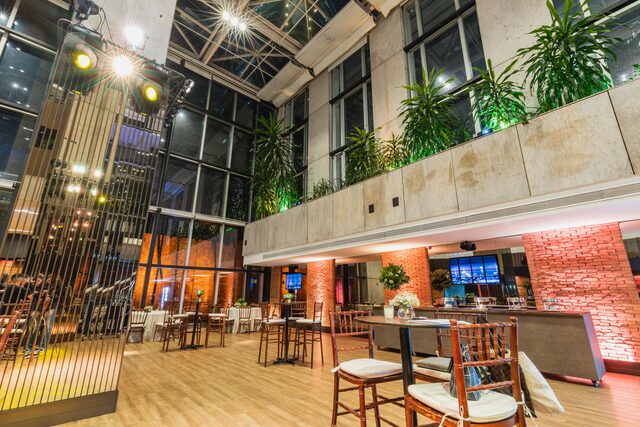 A modern industrial event venue with tall windows, brick walls and stage lighting.