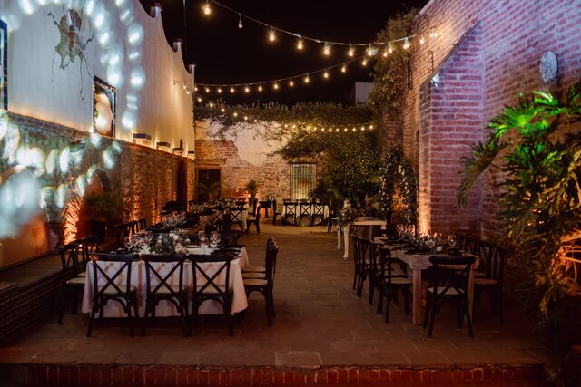 An evening reception set with tables under strings of warm lights.